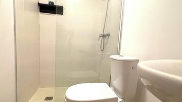 A bathroom with a toilet, a shower enclosure, and a sink.