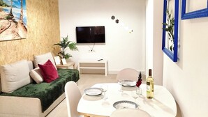 Ein stilvolles Wohnzimmer mit Essbereich, einer Couch, einem Fernseher und Dekorationselementen.