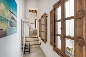 Una escalera conduce a un dormitorio con vistas al mar, puertas de madera y un pequeño rincón de descanso.