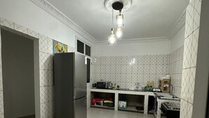 A kitchen with white tiled walls, a refrigerator, a stove, and a sink.