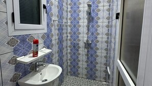 A bathroom with patterned tiles, a sink, a shower, and a toilet.