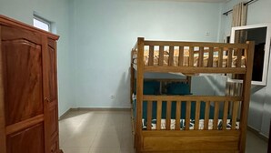 A room with a bunk bed, a wooden wardrobe, and a window.