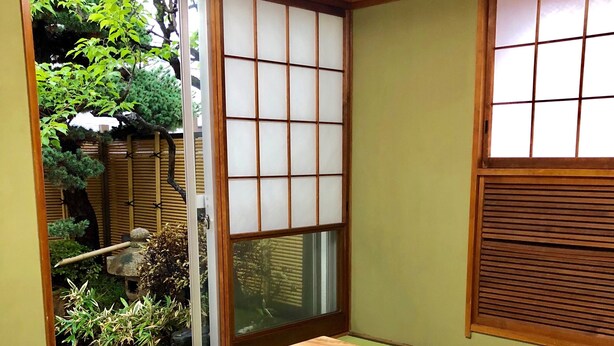 Ein traditioneller japanischer Raum mit Tatami-Bodenbelag, einem niedrigen Tisch mit Teeservice und Shoji-Schirmwänden.