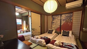 Ein traditioneller japanischer Raum mit Tatami-Boden, zwei Betten mit Kissen, einem Holztisch und einer verschiebbaren Shoji-Schirmwand.