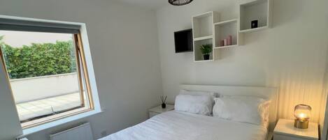 A bedroom with a bed, bedside tables, a window, and a hanging light fixture.