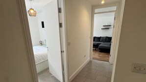 A hallway with a bed in the left room and a sofa in the right room.