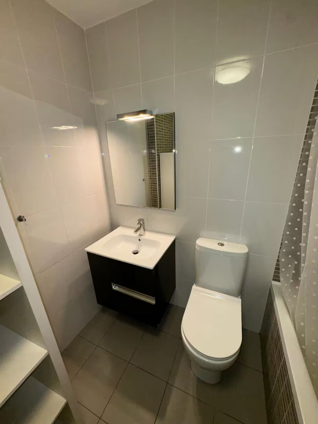 A modern bathroom with a white sink, a toilet, and a mirror.
