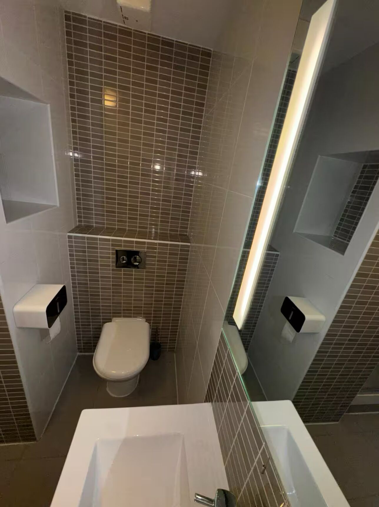 Un baño moderno con inodoro blanco, una bañera amplia y un box de ducha de vidrio.
