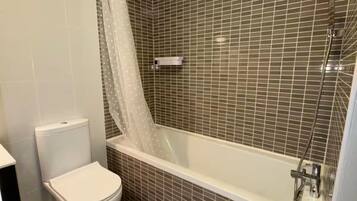 A bathroom with a toilet, a shower with a glass enclosure, and tiled walls.