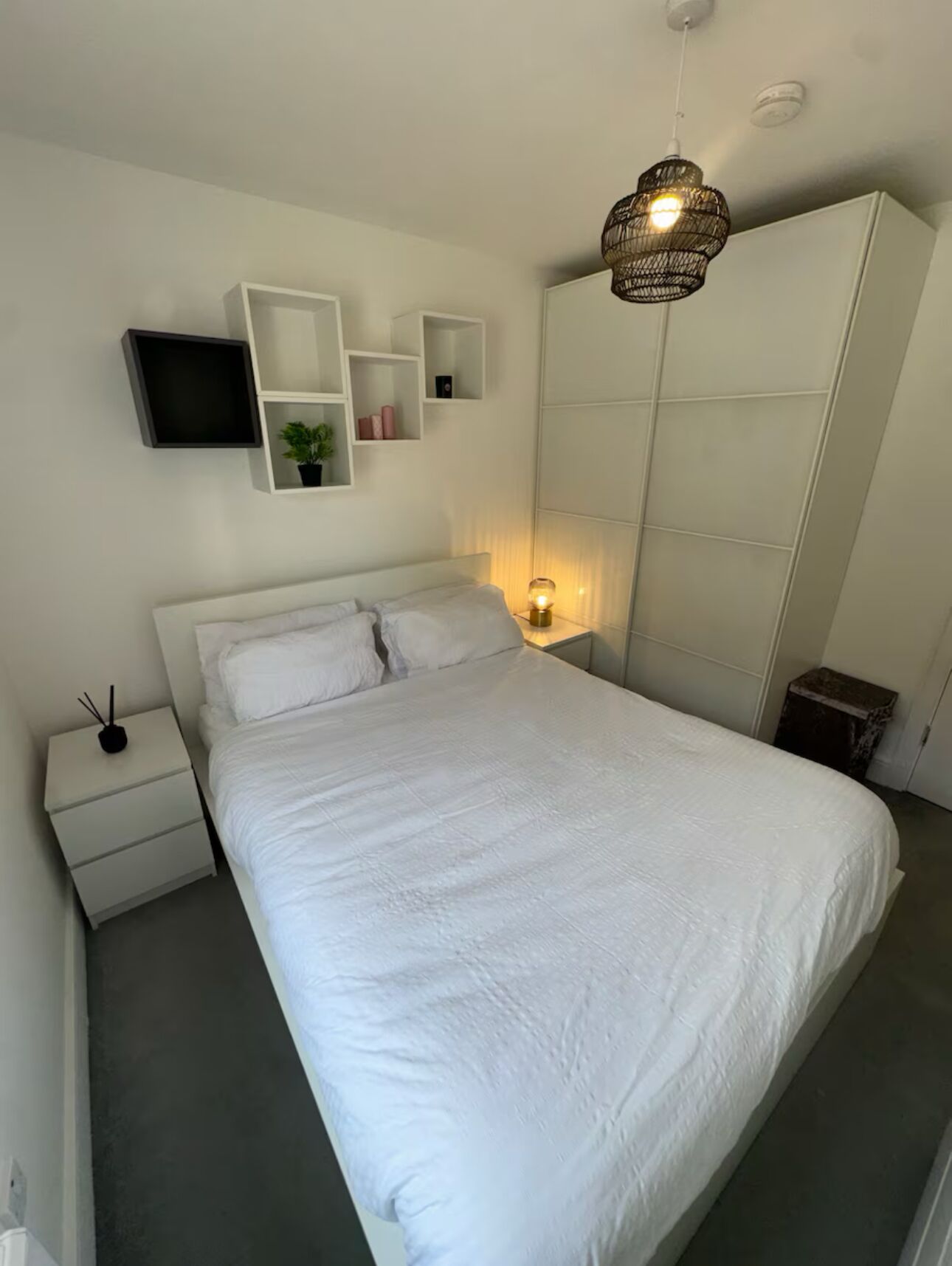 A bedroom with a bed, bedside tables, a TV, and a wardrobe.
