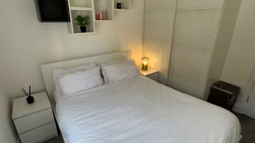 A bedroom with a bed, bedside tables, a TV, and a wardrobe.