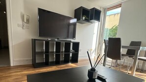 A modern living room with a large flat-screen TV, a dark wooden coffee table, and a minimalist black entertainment unit.