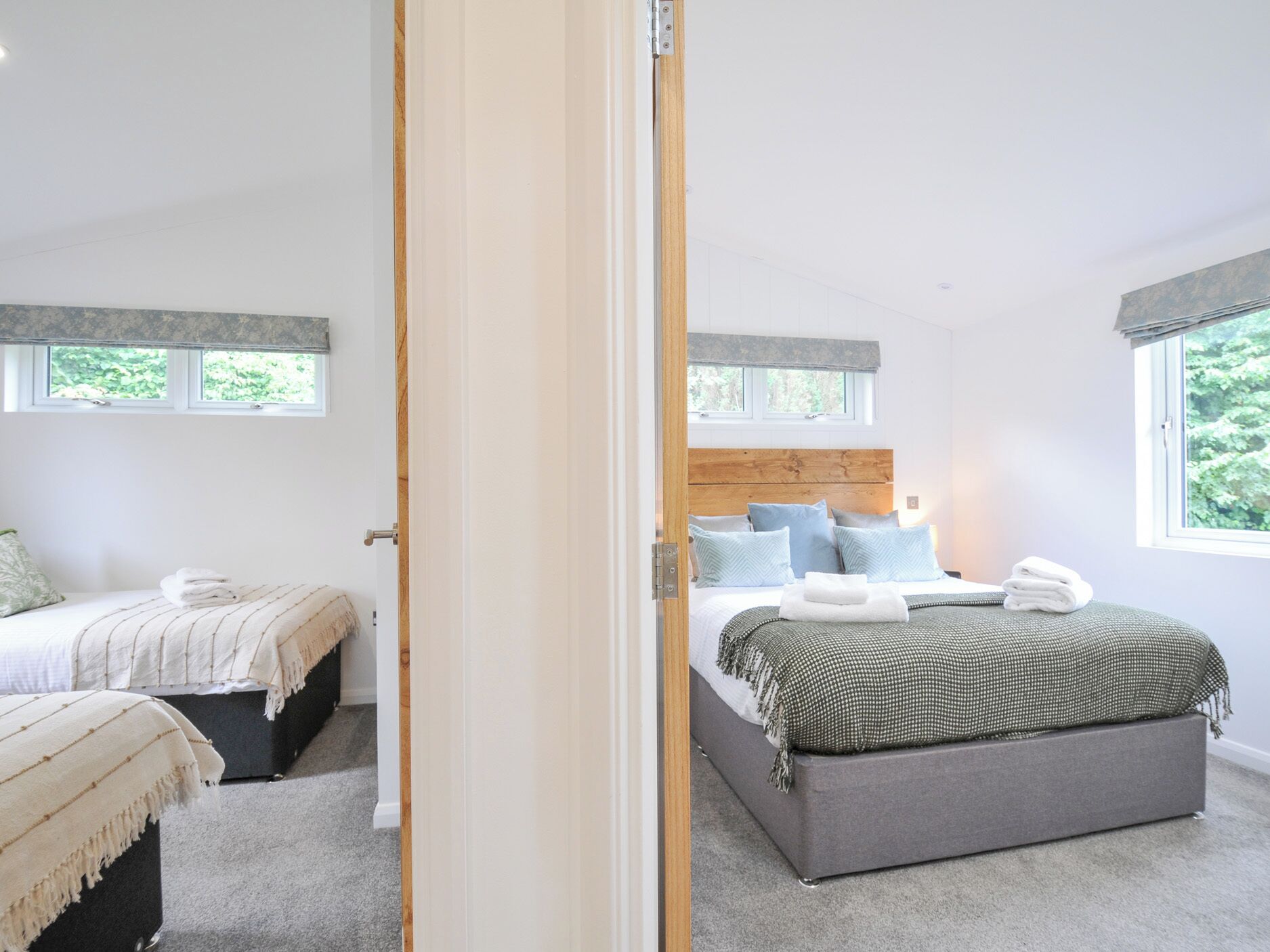 A bedroom with two beds, a wooden headboard, and a large window.