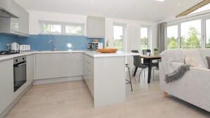 Una cocina moderna con una isla central, un comedor con mesa y sillas, y un sofá en la sala de estar.