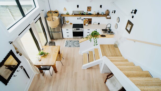 A modern kitchen with a wooden dining table, a staircase, and a view of the outside. - Walk to the Beach! Boho-Inspired 2BR Jupiter Loft w Private Outdoor Space (Jupiter)