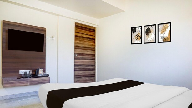 Ein modernes Hotelzimmer mit einem Bett, einem Flachbildfernseher, einem Holzschrank und drei gerahmten Kunstwerken an der Wand.
