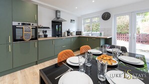 A modern kitchen with a built-in oven, microwave, and gas stove. There is a dining area with a table set for two, and a large window providing a view of the outside.