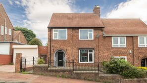 A two-story brick house with a garage, a front door, and a small garden area. - Luke Stays - Lonnen Drive (Swalwell)