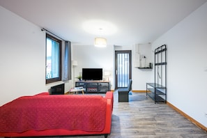 A room with a bed, a TV, a desk, and a window.