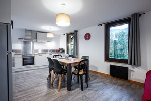 A modern kitchen with a dining area, large windows with a view, and a clock on the wall. - Holiday Home 'Aigueblanche' with Mountain View and Wi-Fi (Grand-Aigueblanche)