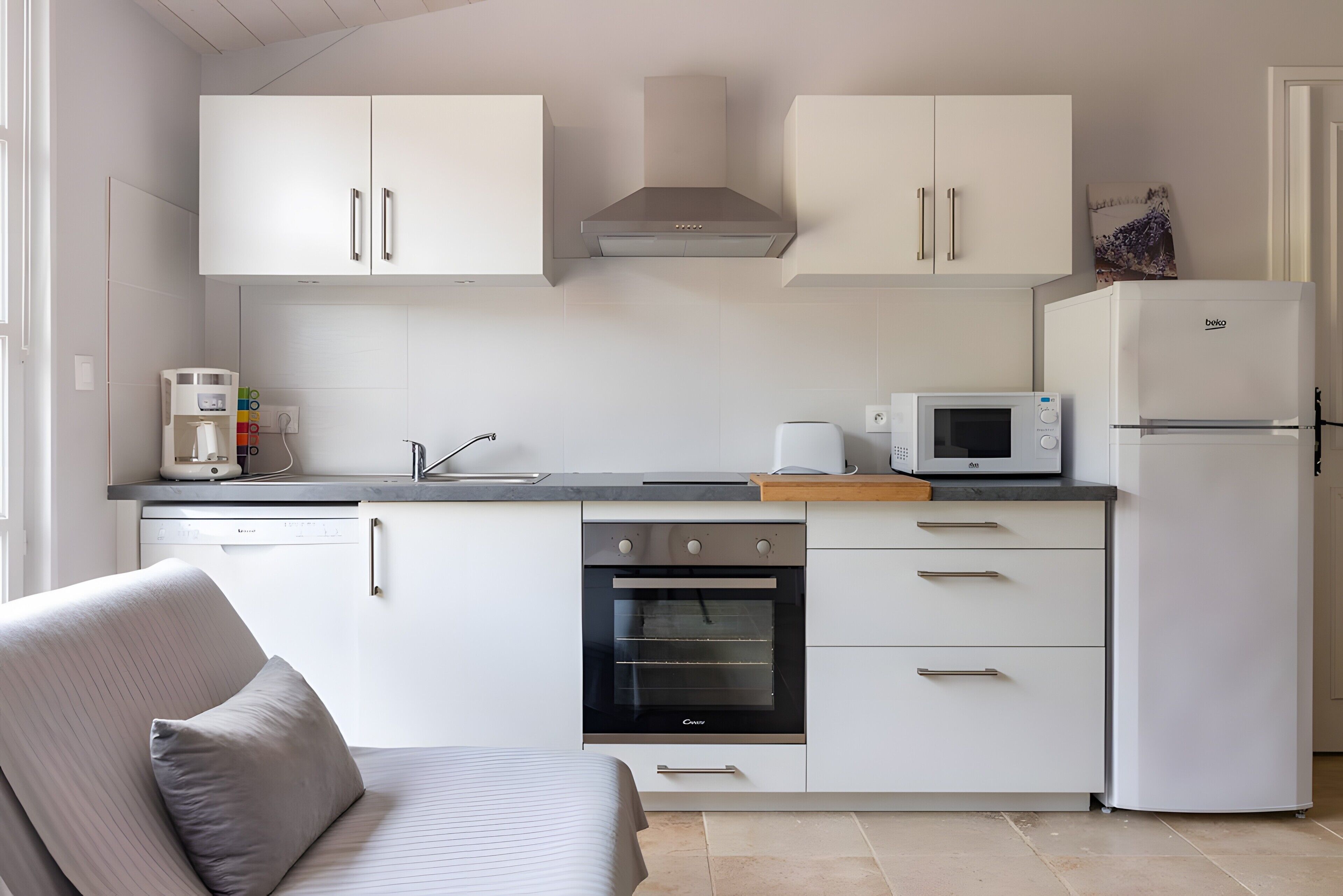Eine moderne Küche mit weißen Schränken, einem eingebauten Backofen, einer Mikrowelle und einem Kühlschrank.