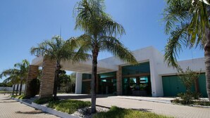 Un edificio moderno con techo plano, amplios ventanales de vidrio y un garaje de color verde.