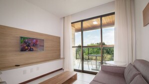 Una sala de estar moderna con un ventanal grande, un sofá, una mesa de centro y un televisor de pared.