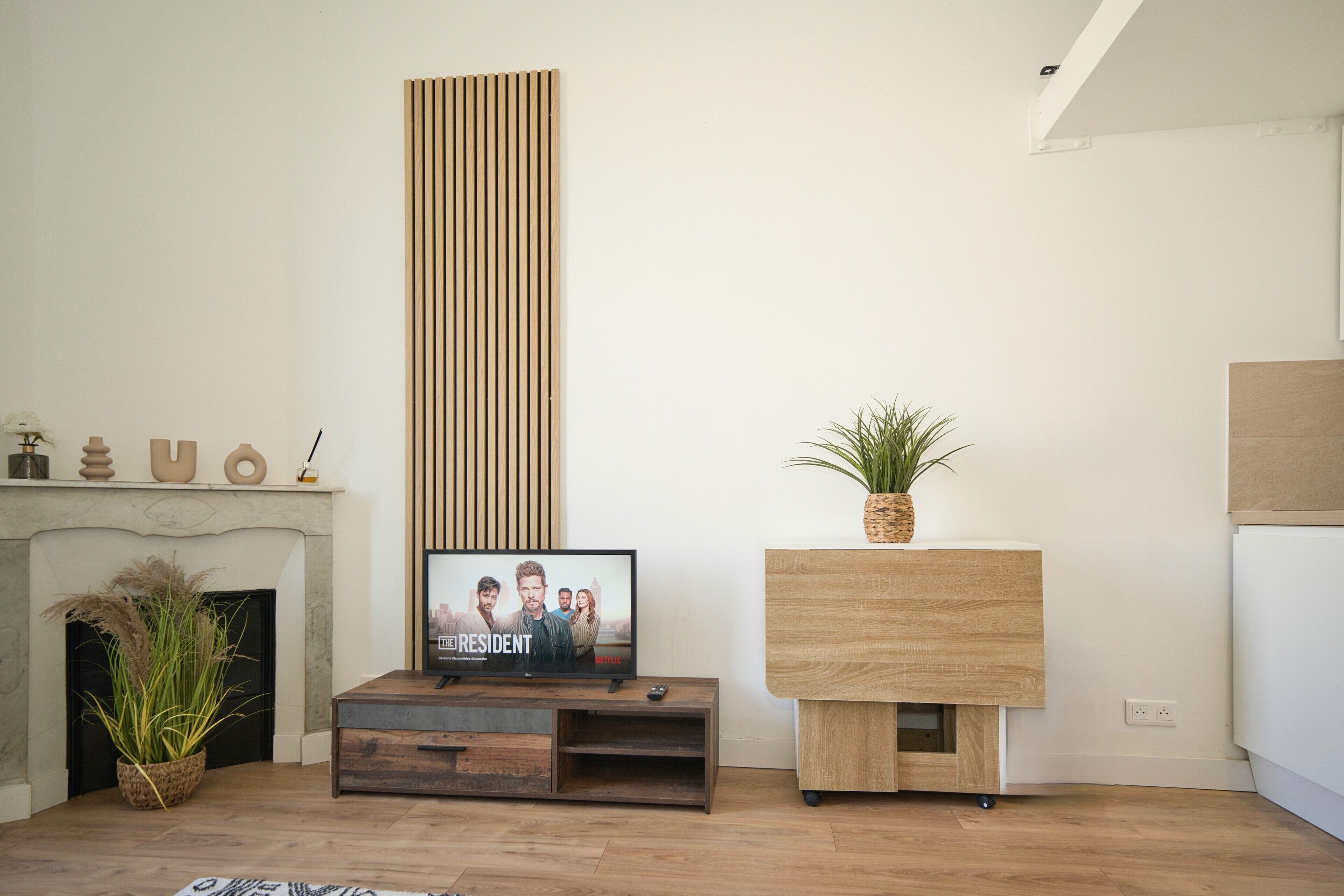A modern living room with a fireplace, a television displaying 'Resident', and a wooden cabinet.