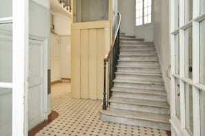 A staircase with a handrail, a patterned floor, and a door leading to another room. - Cosy studio in the center of Nice (Nice)