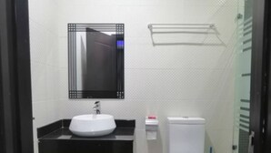 A compact bathroom with a white sink, a mirror, a toilet, and a shower area. - Super Powered Mansion  Room 24hr AC & Power (Ikeja)