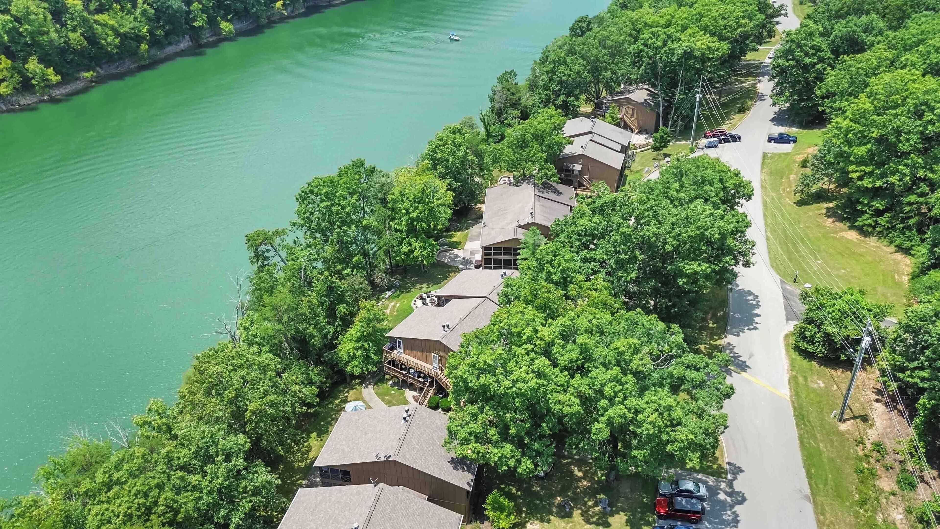 A residential area with houses along a road, a body of water, and a boat.