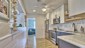 A modern kitchen with white cabinetry, a stainless steel refrigerator, and a microwave. - Coquina Hideaway (St. Pete Beach)