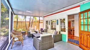 A covered patio area with wicker furniture, a sofa, and a dining table. - Coquina Hideaway (St. Pete Beach)