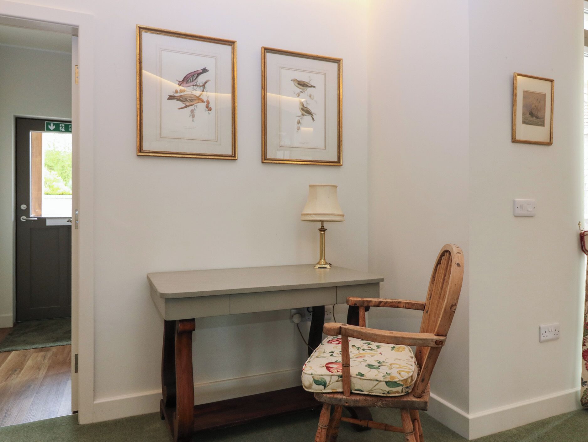A room with a desk, chair, and framed bird illustrations on the wall.