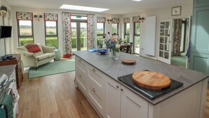 A modern kitchen with a central island, large windows, and a dining area. - Lower Lodge (Cupar)