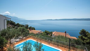 A pool with a view of the sea, surrounded by trees and buildings. - Dodjite i odmorite se u našem predivnom apartmanu (Marušići)