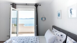 A bedroom with a bed, a view of the sea, a life ring decoration, and a framed picture on the wall. - Dodjite i odmorite se u našem predivnom apartmanu (Marušići)