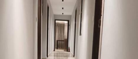 A long, narrow hallway with a shiny tiled floor and white walls.
