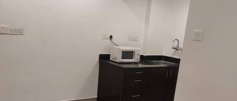 A clean, modern kitchen with a microwave, dark cabinets, and a tiled floor.