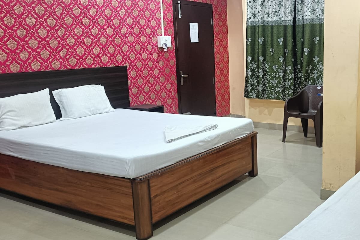 Um quarto com cama de madeira, mesa de cabeceira, cadeira e porta.