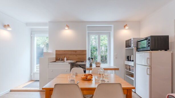 Una cocina moderna con armarios blancos, encimera de madera y comedor con dos sillas y una mesa para dos.