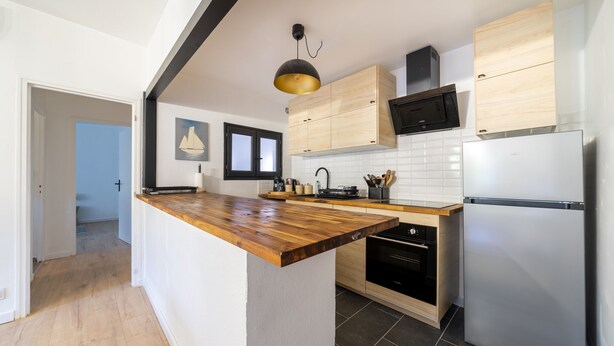 A modern kitchen with wooden cabinetry, a built-in oven, and a stainless steel refrigerator. - L'Écrin de Beaucaire - Climatisé, à 30 min d'Arles (Beaucaire)