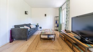 A modern living room with a sofa, coffee table, and TV. - L'Écrin de Beaucaire - Climatisé, à 30 min d'Arles (Beaucaire)