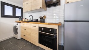 A modern kitchen with wooden cabinets, a built-in oven, a washing machine, and a stainless steel refrigerator. - L'Écrin de Beaucaire - Climatisé, à 30 min d'Arles (Beaucaire)