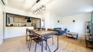 A modern kitchen with wooden cabinets, a dining table with chairs, a sofa, and a coffee table. - L'Écrin de Beaucaire - Climatisé, à 30 min d'Arles (Beaucaire)