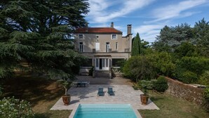 A two-story house with a swimming pool, surrounded by trees and a patio area with chairs. - Villa Corbière - Piscine Privée (Castres)