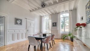 A dining area with a large table, chairs, and a ceiling fan. - Villa Corbière - Piscine Privée (Castres)