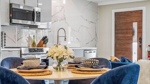 Una cocina moderna con armarios blancos, microondas integrado y horno de acero inoxidable.