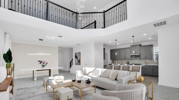 A spacious living area with a white sofa set, a coffee table, and a dining table. There is a staircase leading to an upper level. - Batman | Mickey | Game Room | 4 Miles Disney 2669 (Kissimmee)