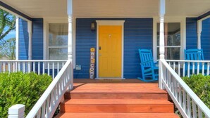A two-story house with a porch, a yellow door, and a 'WELCOME' sign.